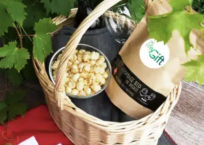 Un panier garni personnalisé en osier, d'origine suisse et composé d'un sachet de pop-corn salé et d'une bouteille de vin pour offrir à des collaborateurs ou des clients